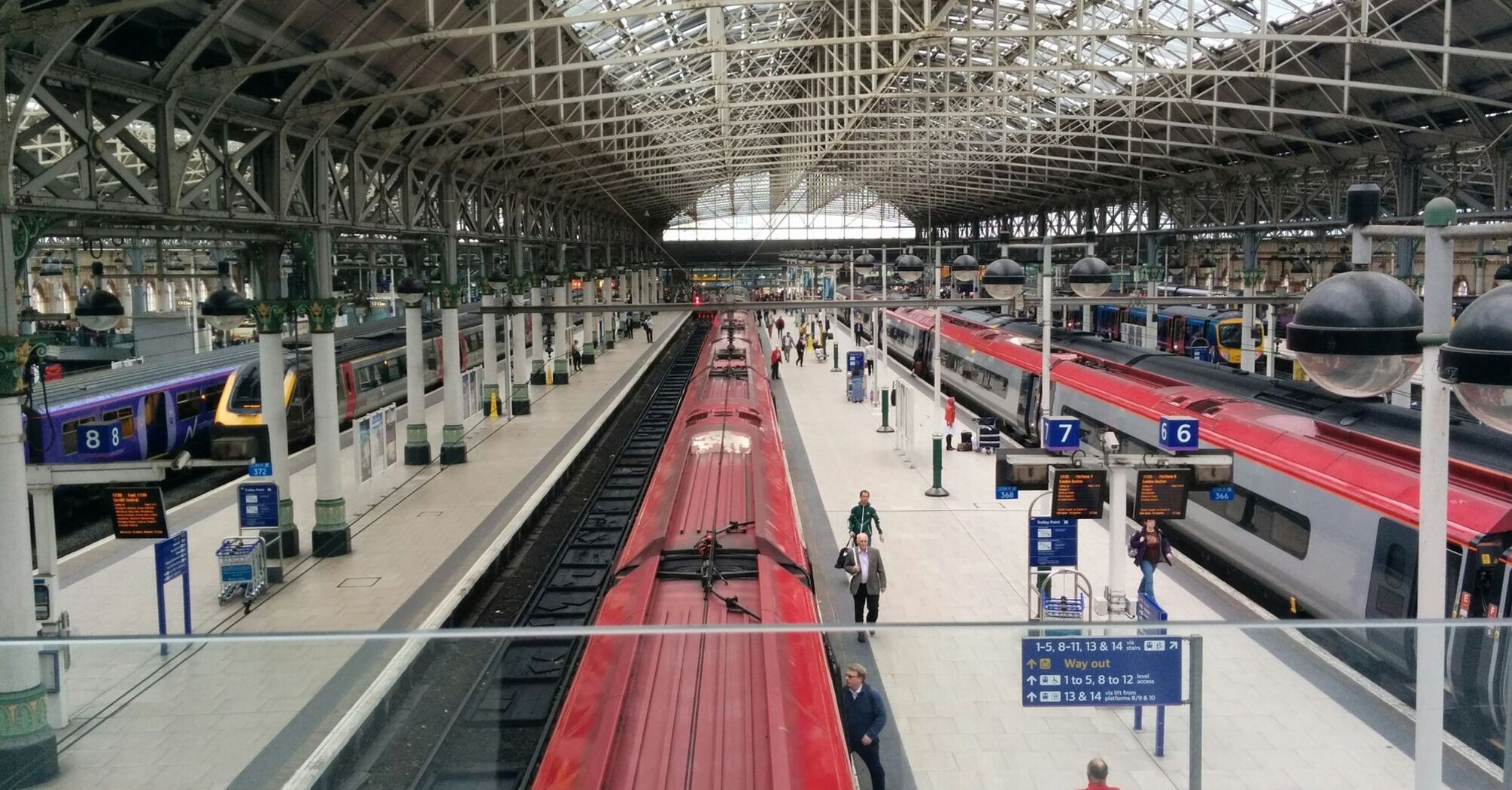 View of platforms and trains at Manchester Piccadilly station with passengers walking and waiting