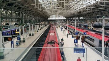 View of platforms and trains at Manchester Piccadilly station with passengers walking and waiting