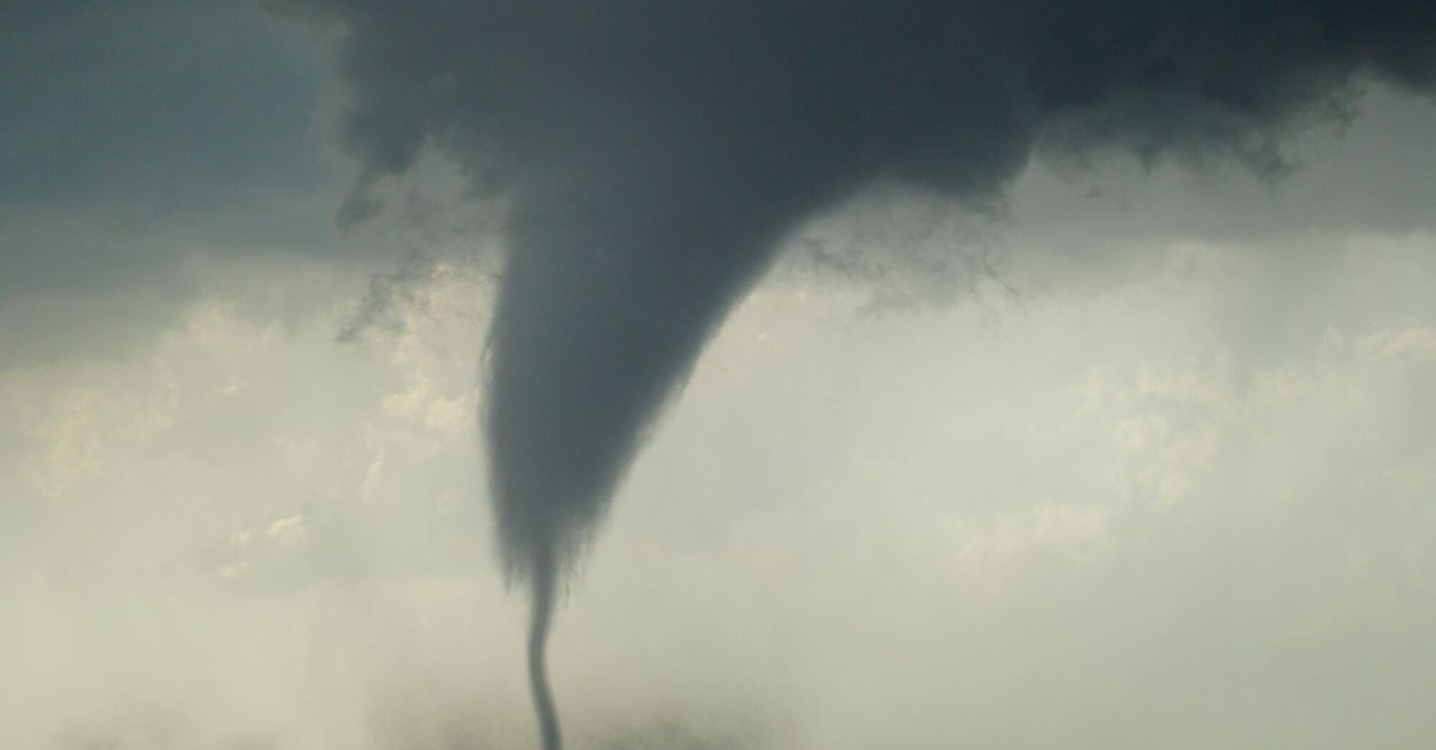 A powerful tornado forming over a flat landscape