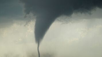 A powerful tornado forming over a flat landscape