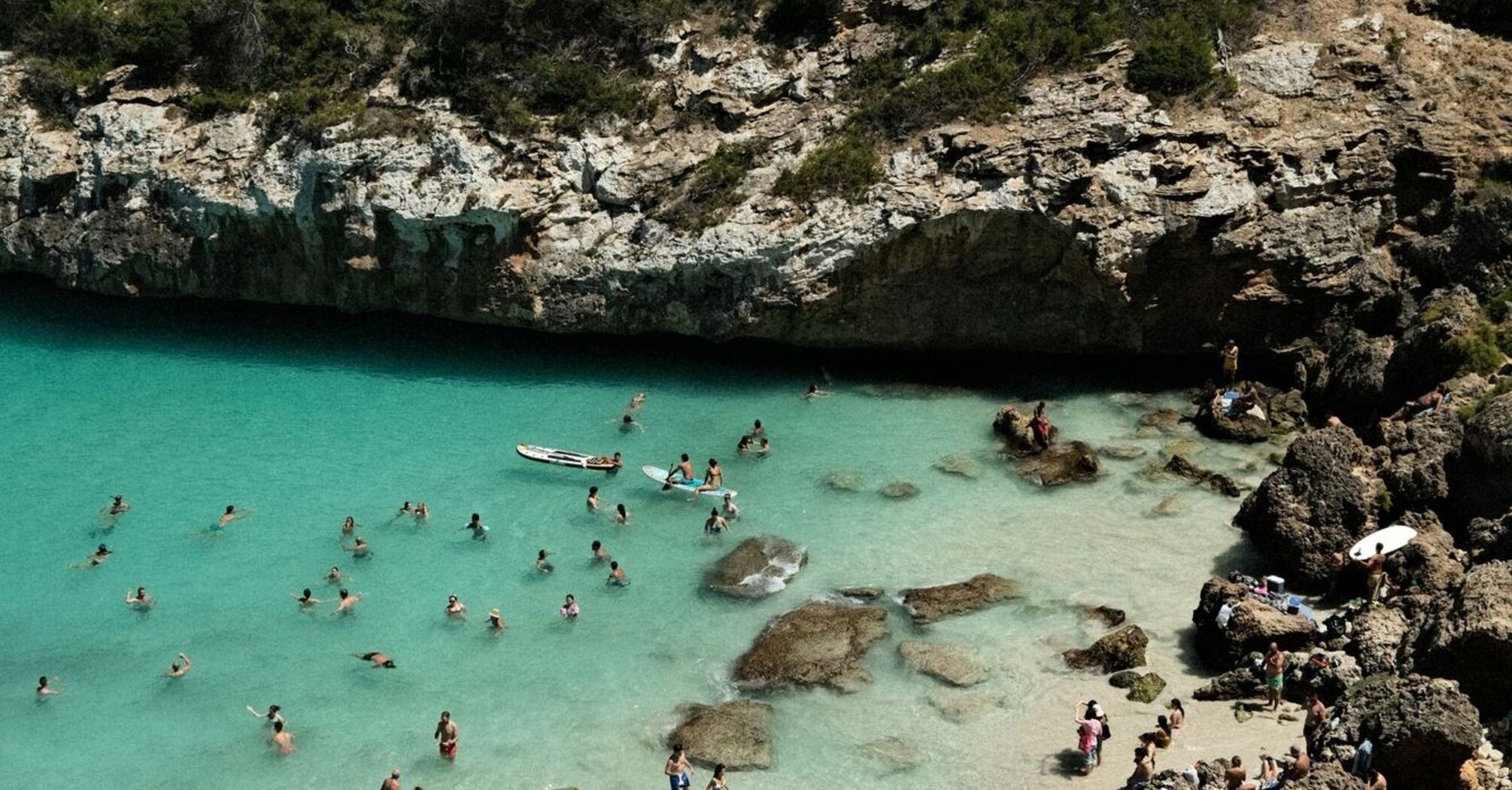 Crowded beach in Mallorca with tourists swimming and sunbathing