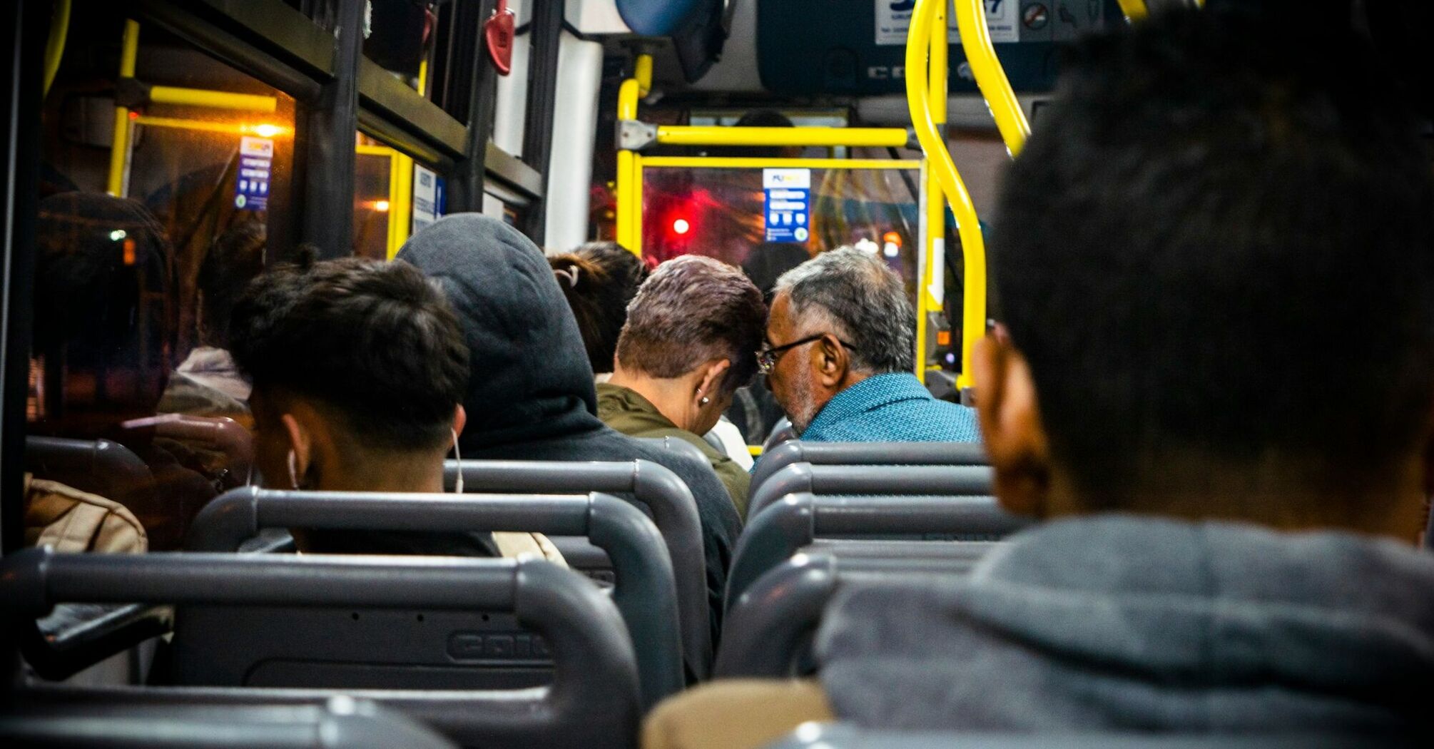 A diverse group of passengers sitting inside a bus during a night journey, highlighting a casual and comfortable atmosphere