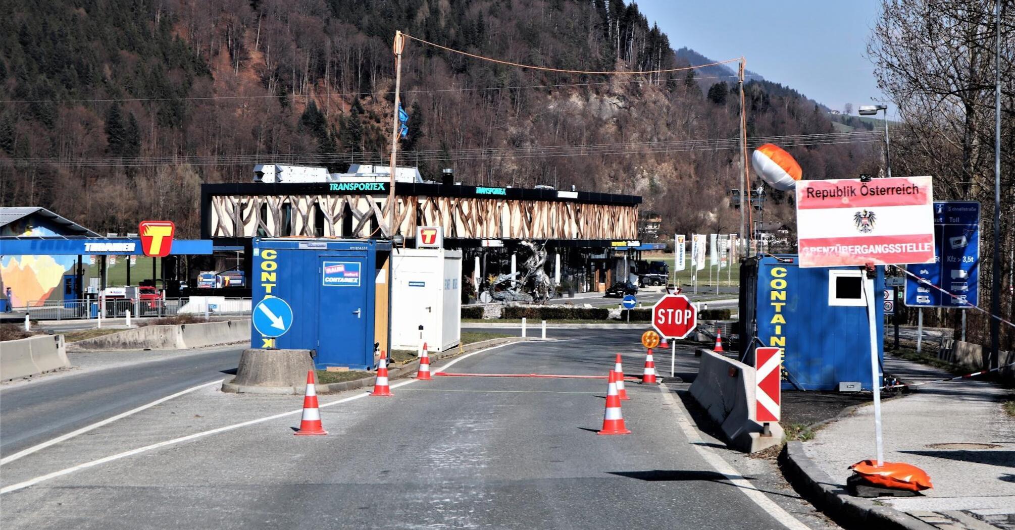 Border checkpoint between Austria and another European country with signs and barriers