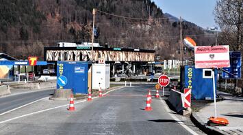Border checkpoint between Austria and another European country with signs and barriers