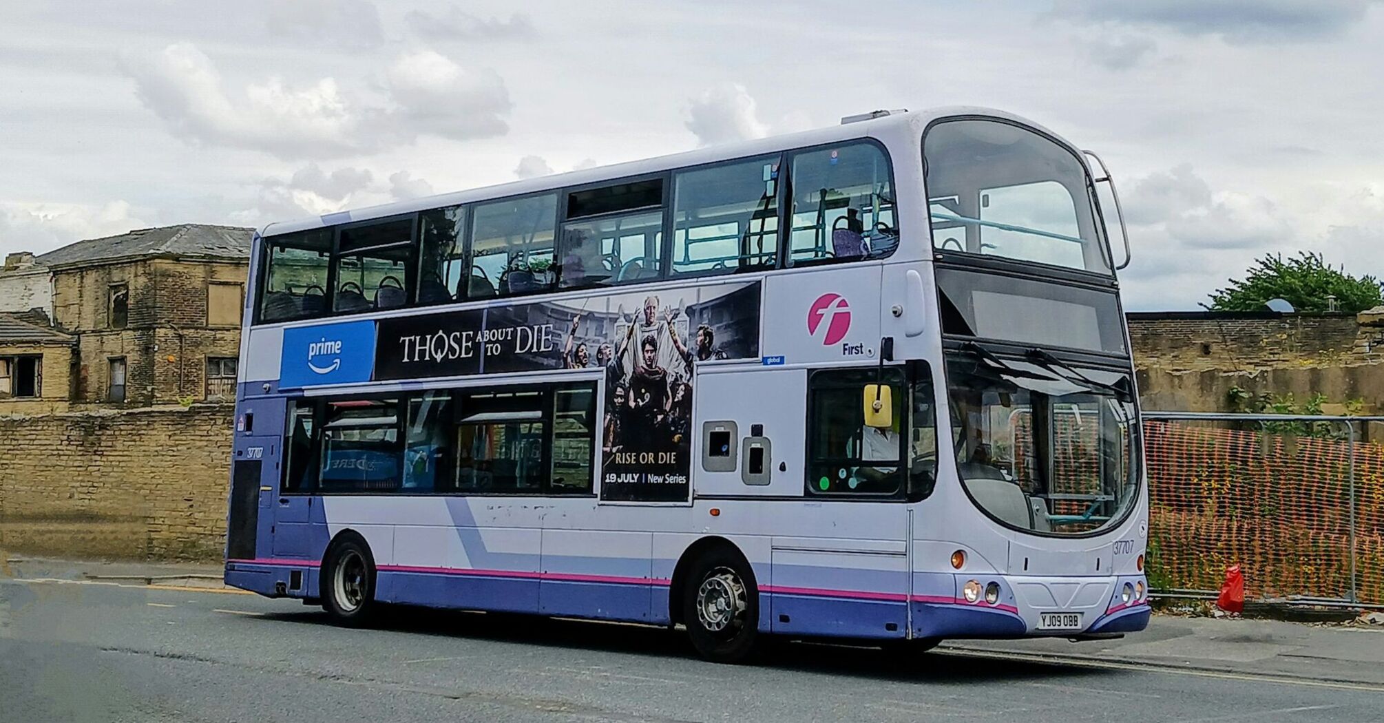 Double-decker First Bus with advertising banner parked in a city street