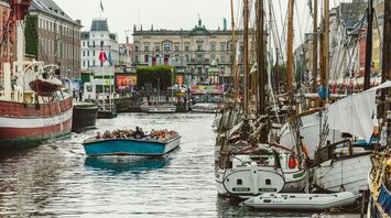 Tourists enjoying a boat ride in a Copenhagen canal surrounded by historic buildings and moored boats