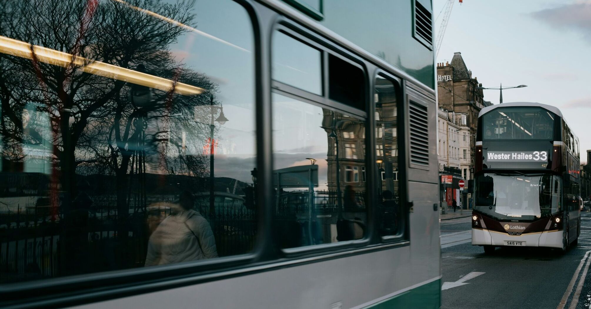 A Lothian double-decker bus on the number 33 route driving through a street in Edinburgh during early evening