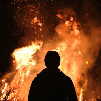 Silhouette of a person standing in front of a large fire