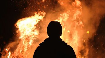 Silhouette of a person standing in front of a large fire