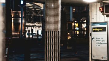 A tiled pillar and station signage at London Liverpool Street station at night