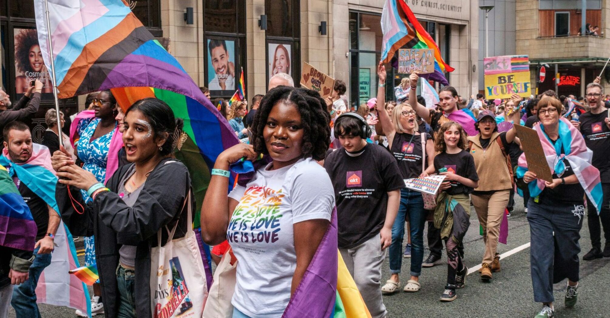 People participating in a Pride march in Manchester, holding colorful flags and banners