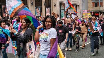 People participating in a Pride march in Manchester, holding colorful flags and banners