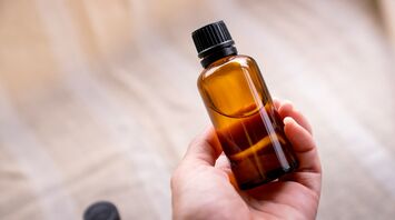 A hand holding a small brown glass bottle