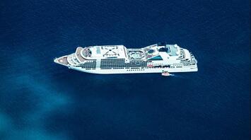 Aerial view of a large cruise ship sailing through deep blue ocean waters