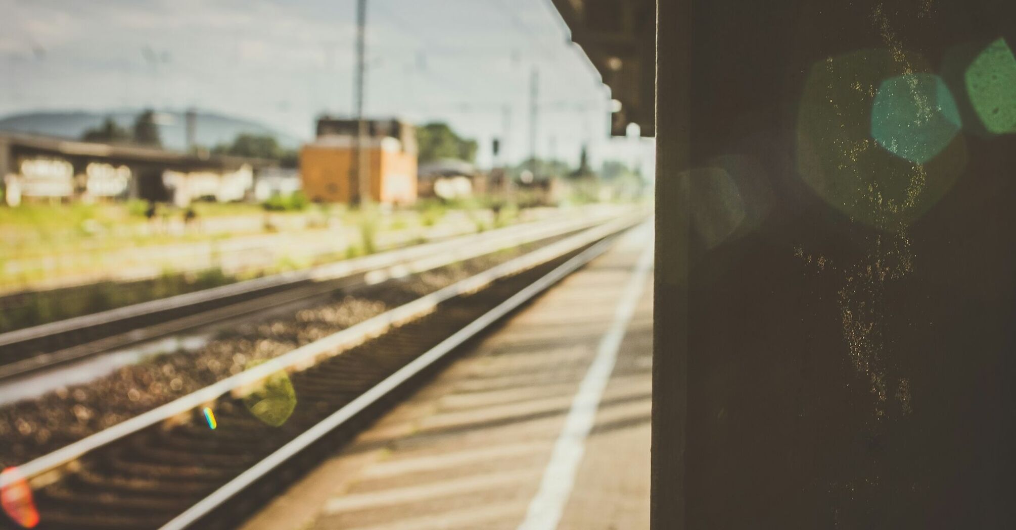 Empty railway platform with tracks extending into the distance under bright sunlight