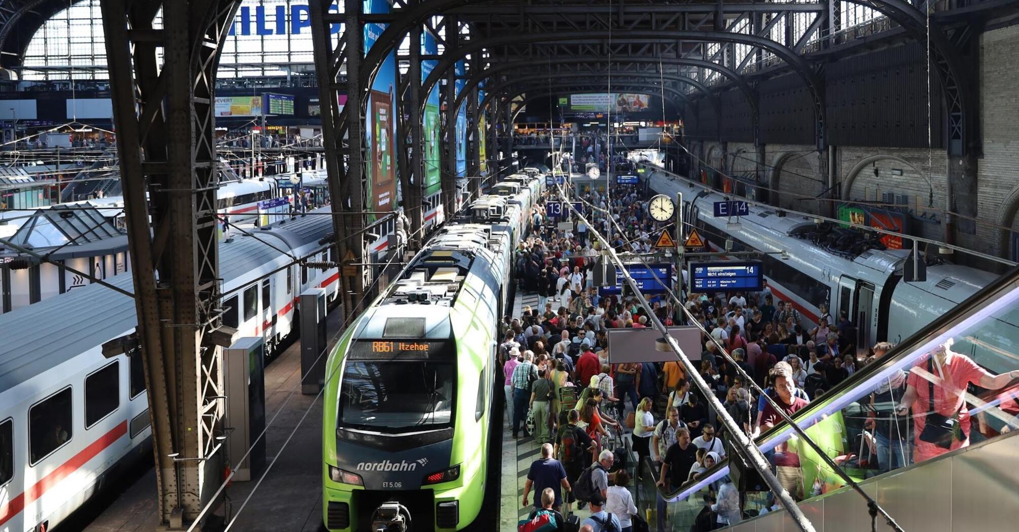 Busy train station with crowded platforms and multiple trains, reflecting travel disruptions