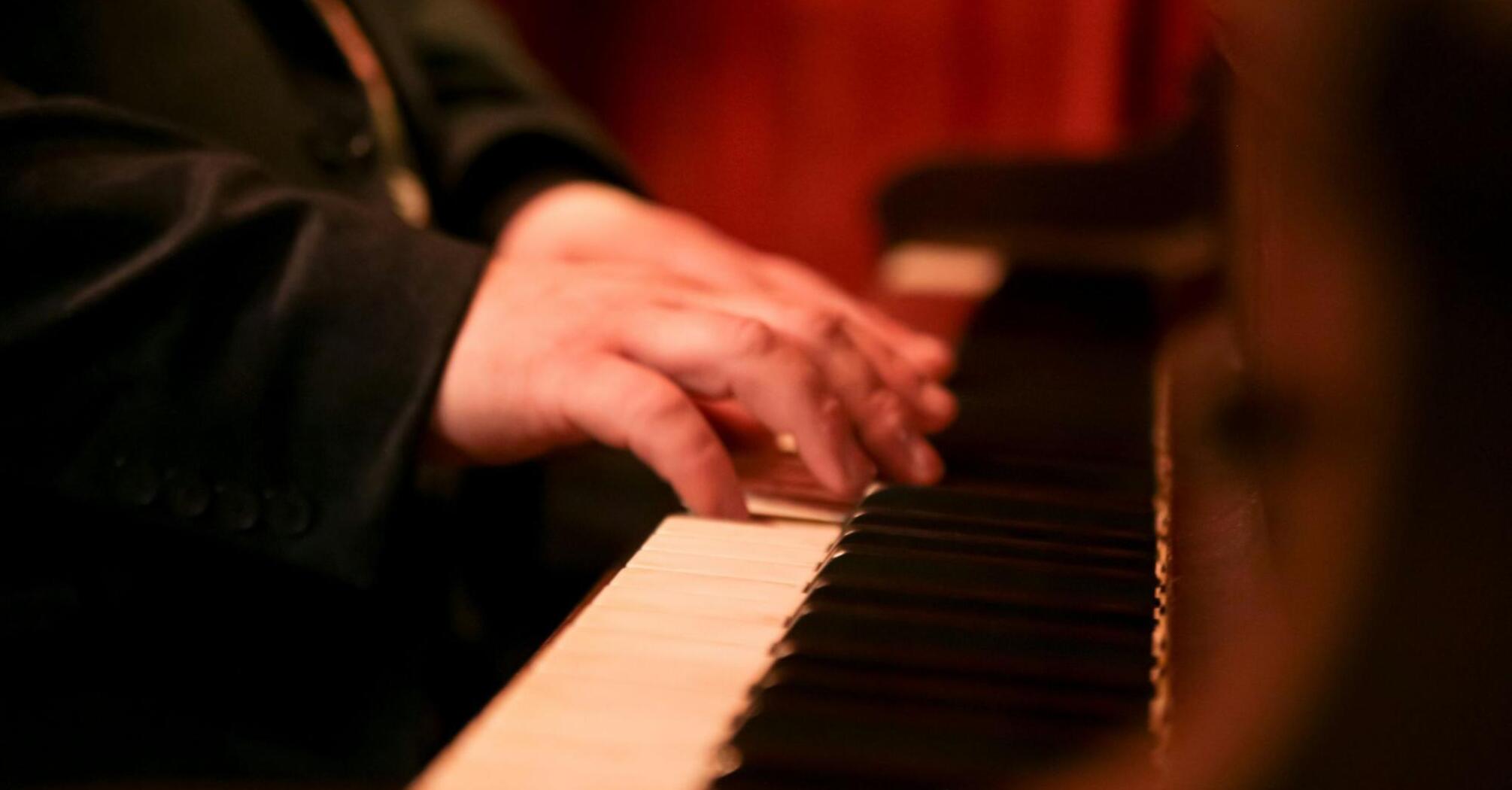 Close-up of a pianist's hands playing the keys of a grand piano