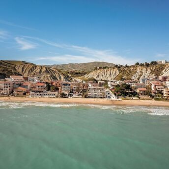 Coastal town in Sicily with beachside houses nestled against rocky hills