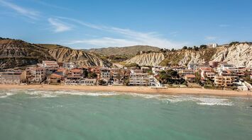 Coastal town in Sicily with beachside houses nestled against rocky hills