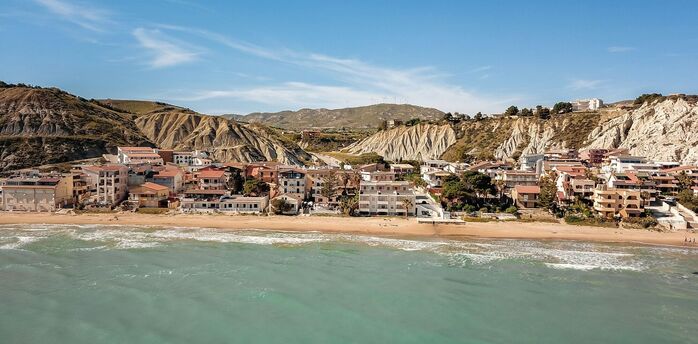 Coastal town in Sicily with beachside houses nestled against rocky hills