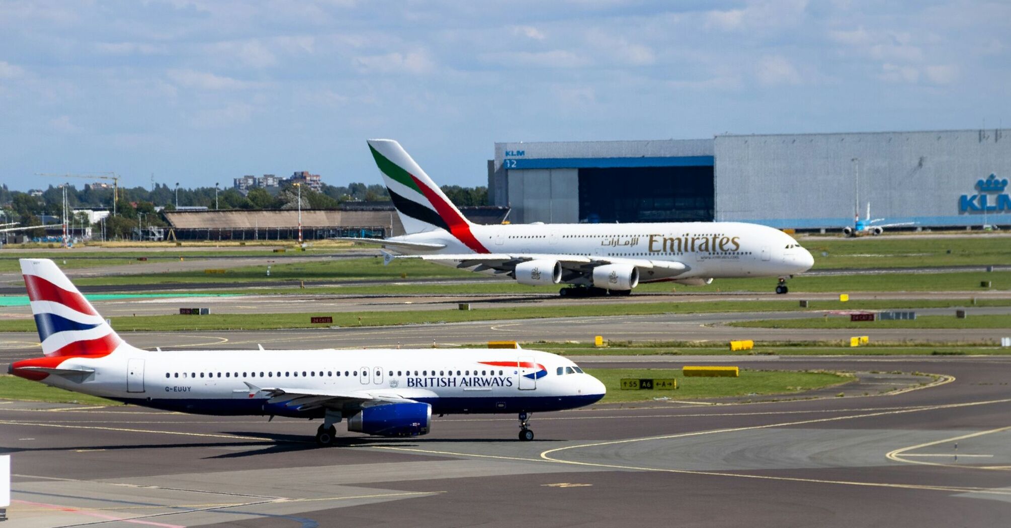 A British Airways and an Emirates airplane on the runway