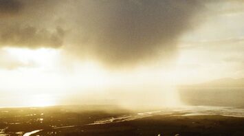 A dark storm cloud looms over a vast landscape with rivers winding through fields, reflecting the dim sunlight as the storm approaches