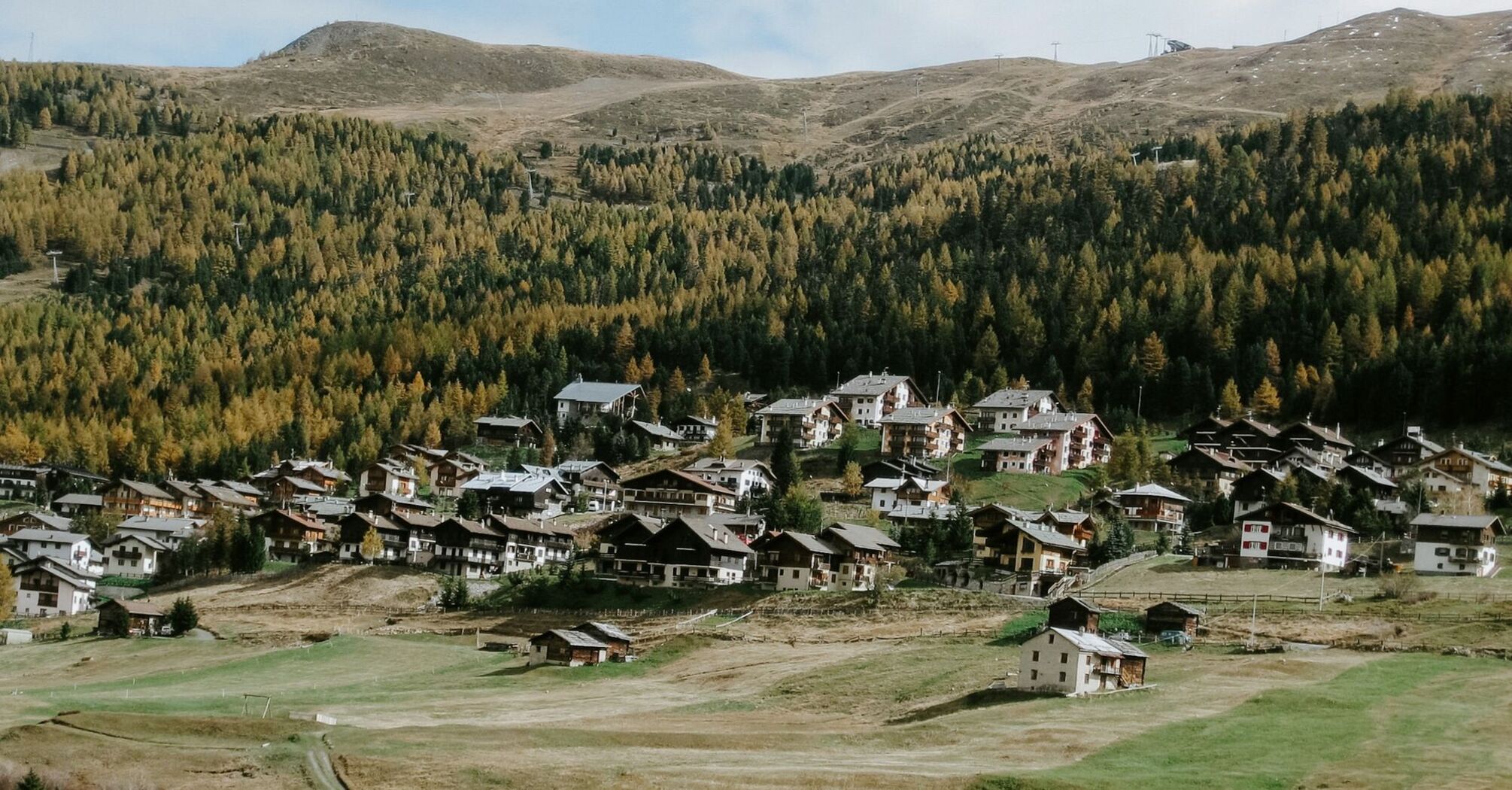 A village nestled in a valley surrounded by forested hills in a mountainous region