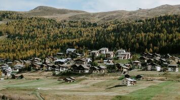 A village nestled in a valley surrounded by forested hills in a mountainous region