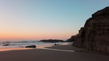 Sunset view of a serene beach with rocks and gentle waves in Galicia