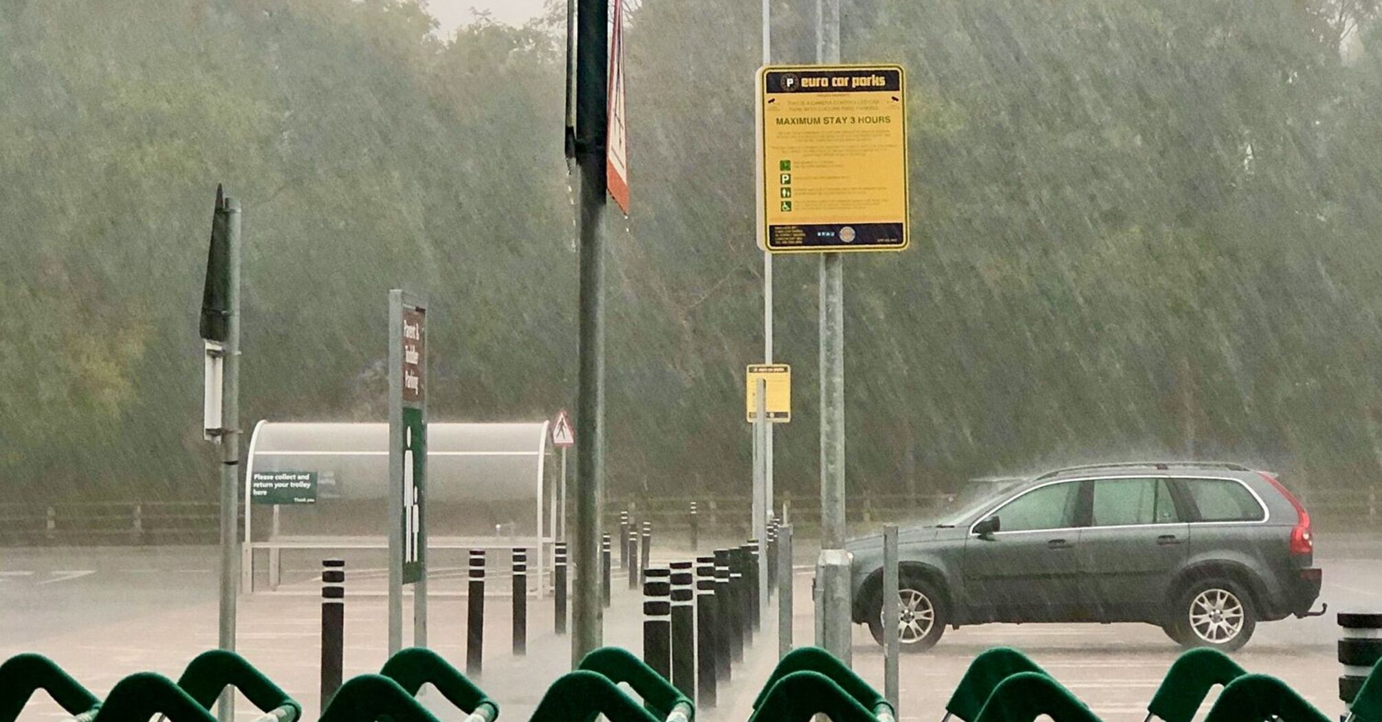 Heavy rain pouring down in a parking lot with shopping carts in the foreground