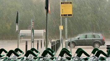 Heavy rain pouring down in a parking lot with shopping carts in the foreground