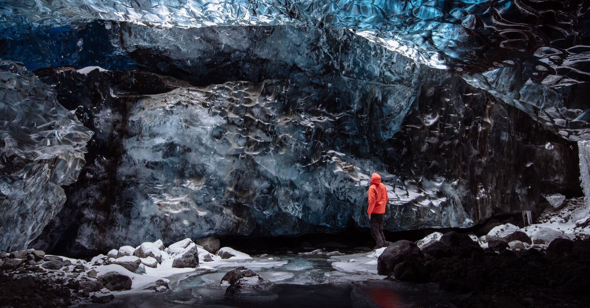 Person standing inside a blue ice cave