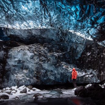 Person standing inside a blue ice cave