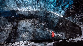 Person standing inside a blue ice cave