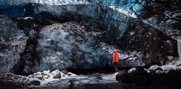 Person standing inside a blue ice cave