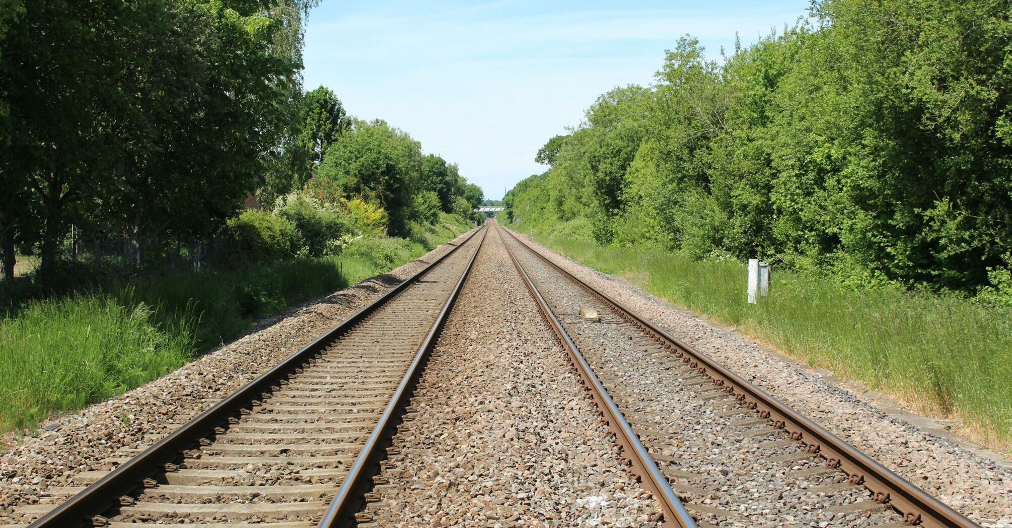 Railway tracks stretching through a green landscape on a clear day