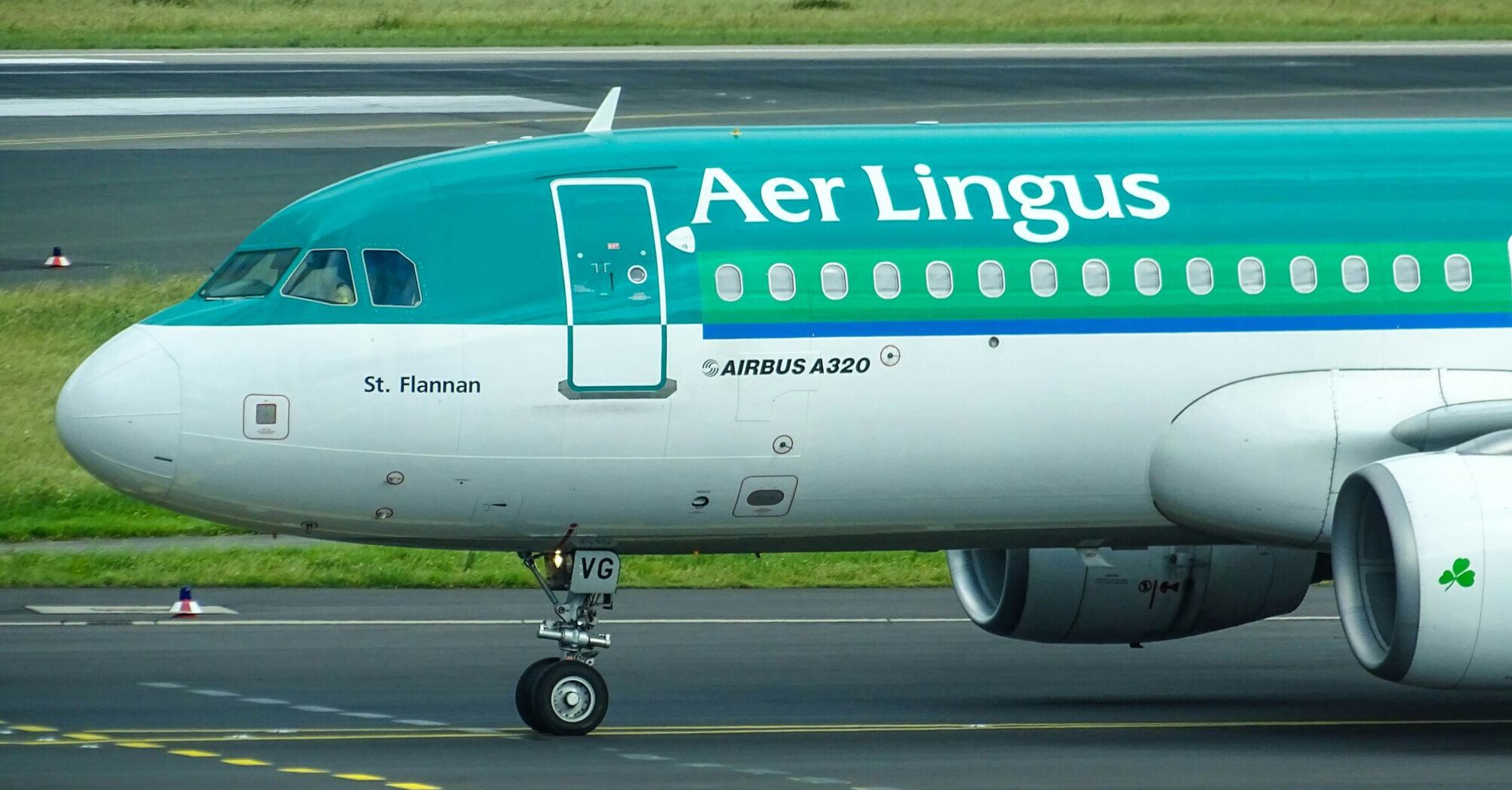 green and white aer lingus plane landing on railway