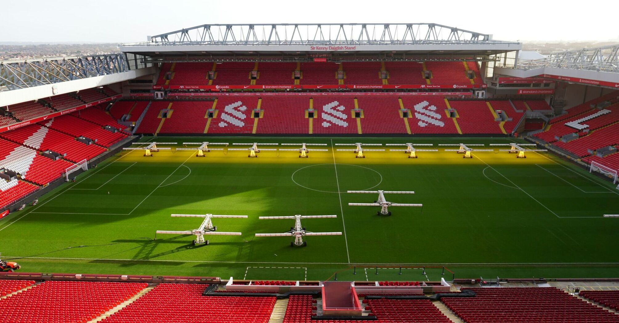 Empty Anfield Stadium with the pitch being maintained under sunlight lamps