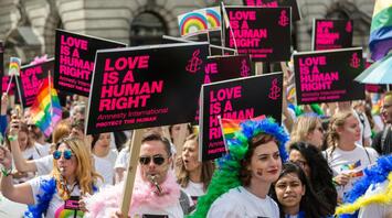 A crowd at a Pride parade holding signs that say "Love is a Human Right"