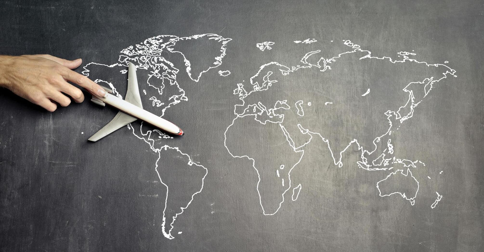 A toy airplane on a world map drawn on a chalkboard