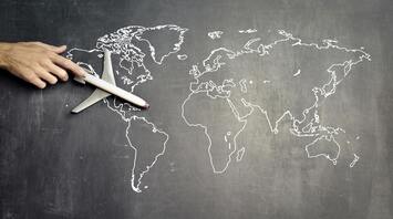 A toy airplane on a world map drawn on a chalkboard