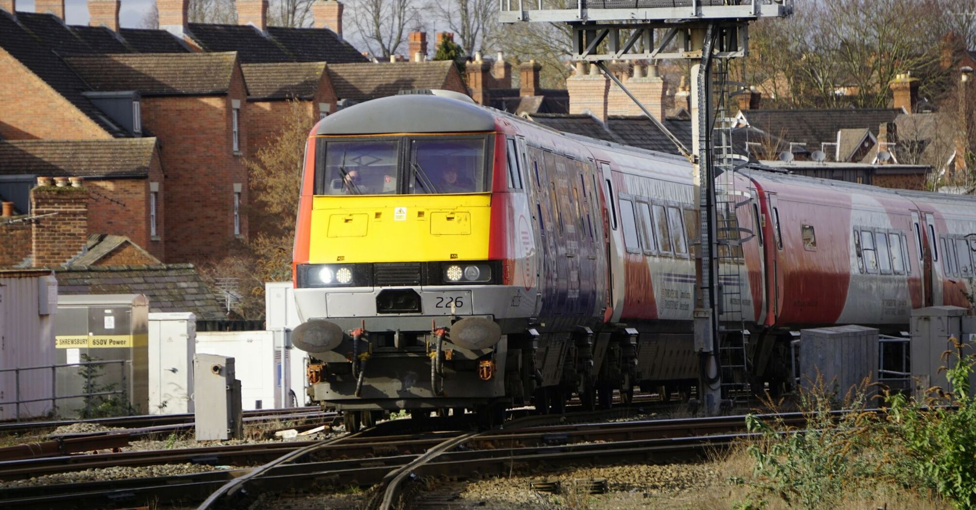 A train traveling through a residential area with brick houses and railway infrastructure visible