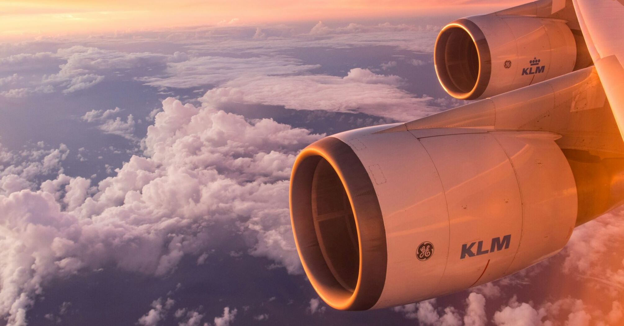 Aerial view of a airplane engine flying above clouds during sunset