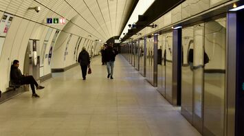 A quiet, spacious platform of the Elizabeth line with a few passengers walking and sitting, reflecting the modern design of the station