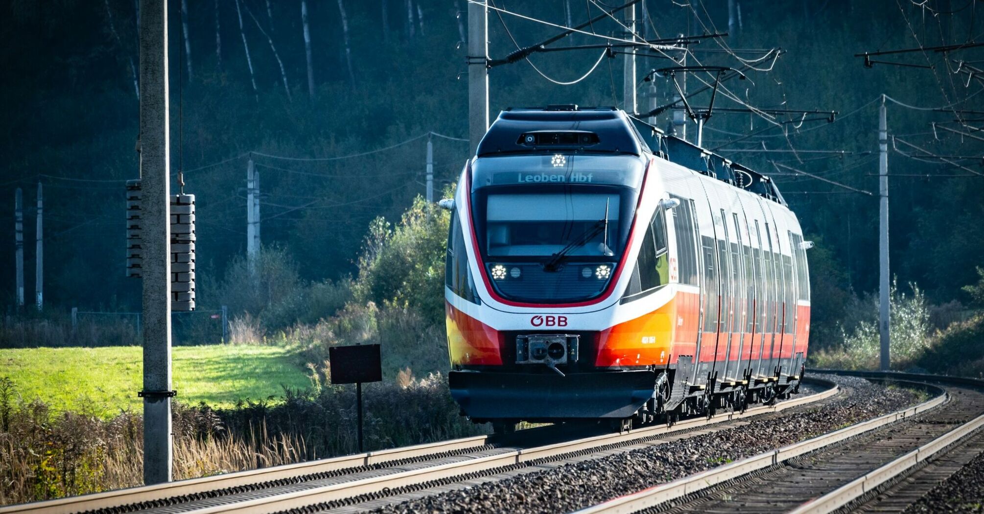 ÖBB train traveling through a scenic route on a sunny day