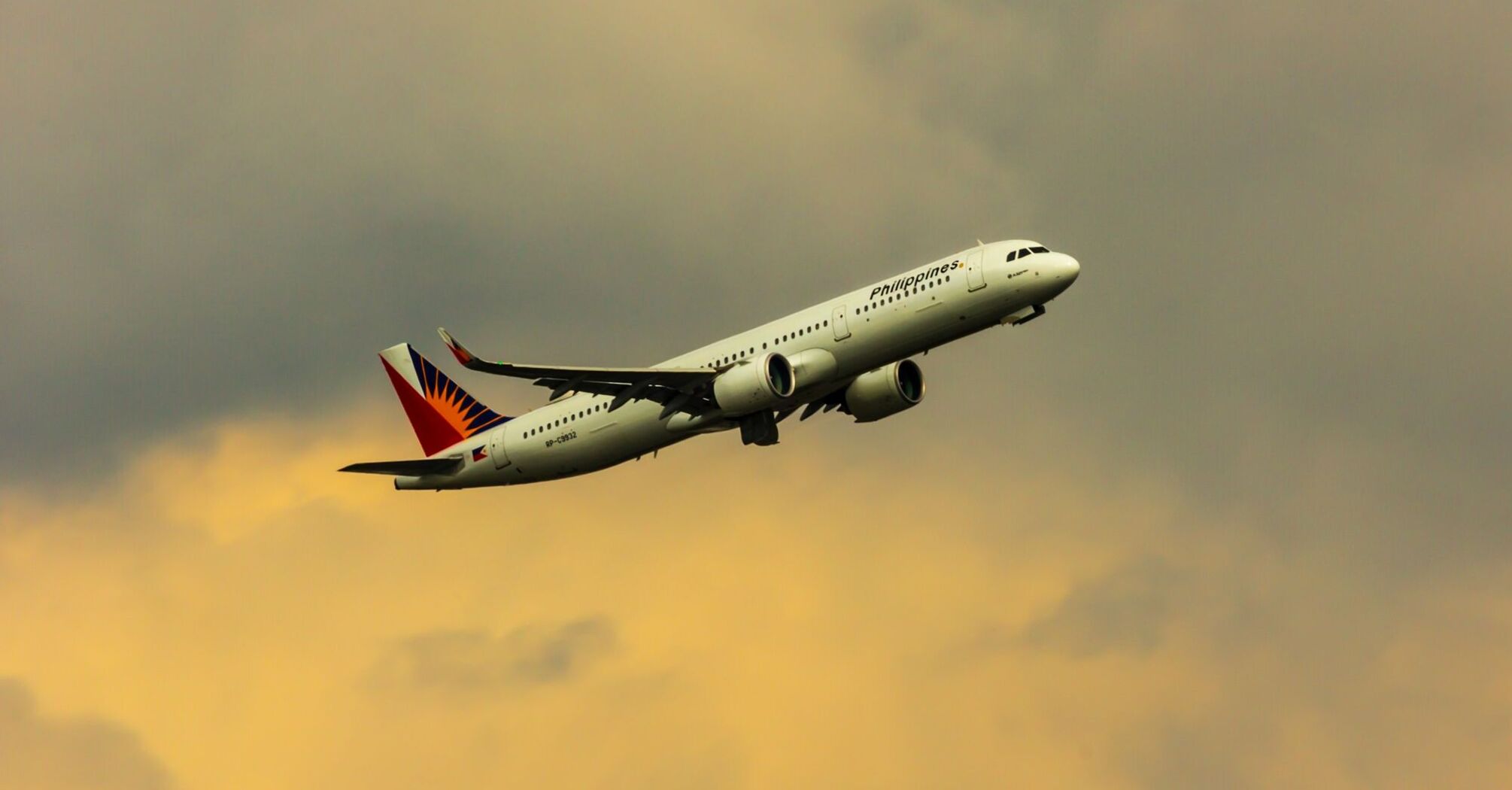 A Philippine Airlines aircraft taking off against a backdrop of a cloudy sky