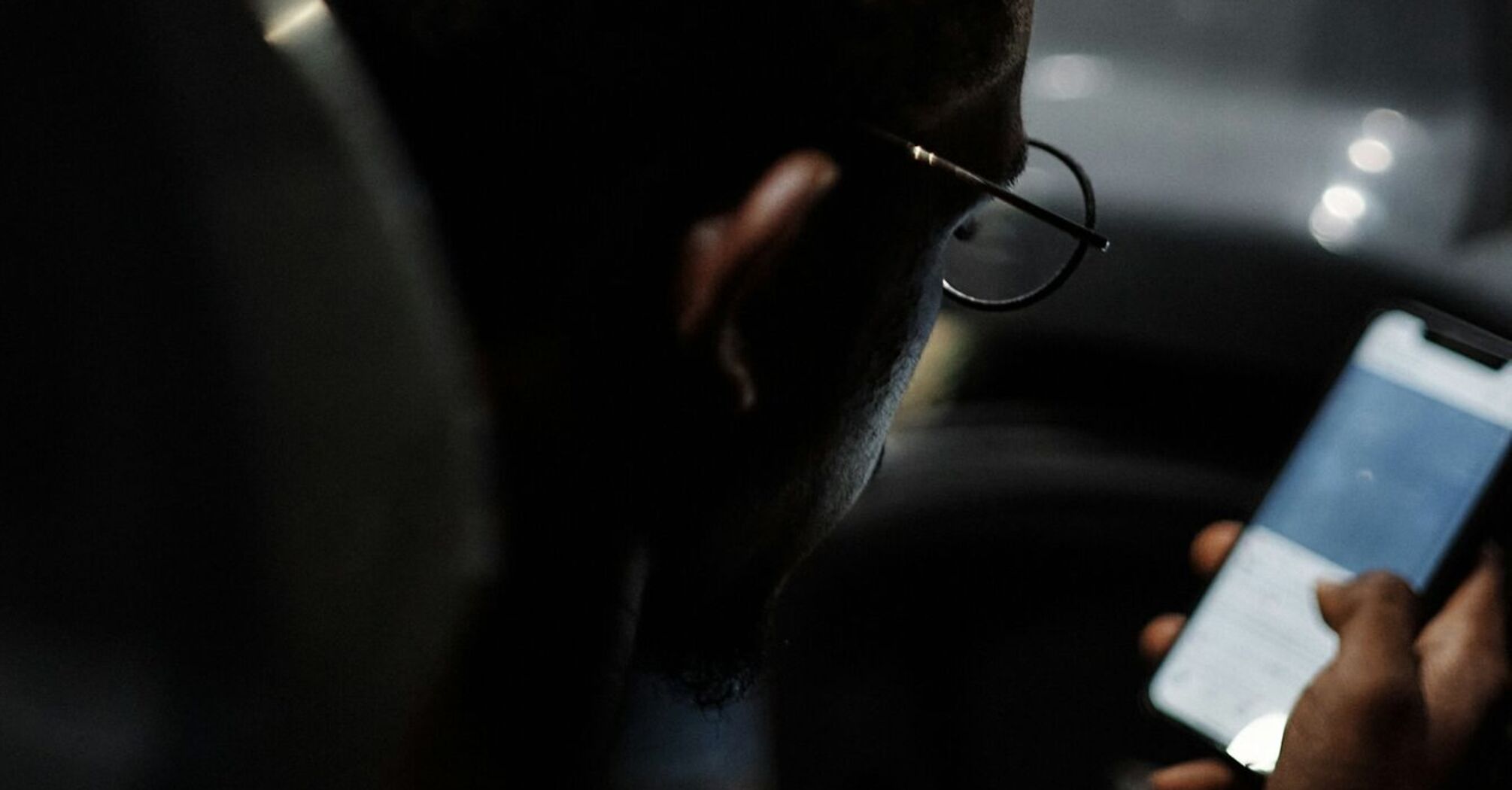 A young person holding onto a bus rail while looking at their phone