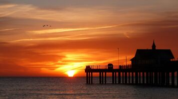 Sunset view over the ocean with a pier silhouette in Suffolk