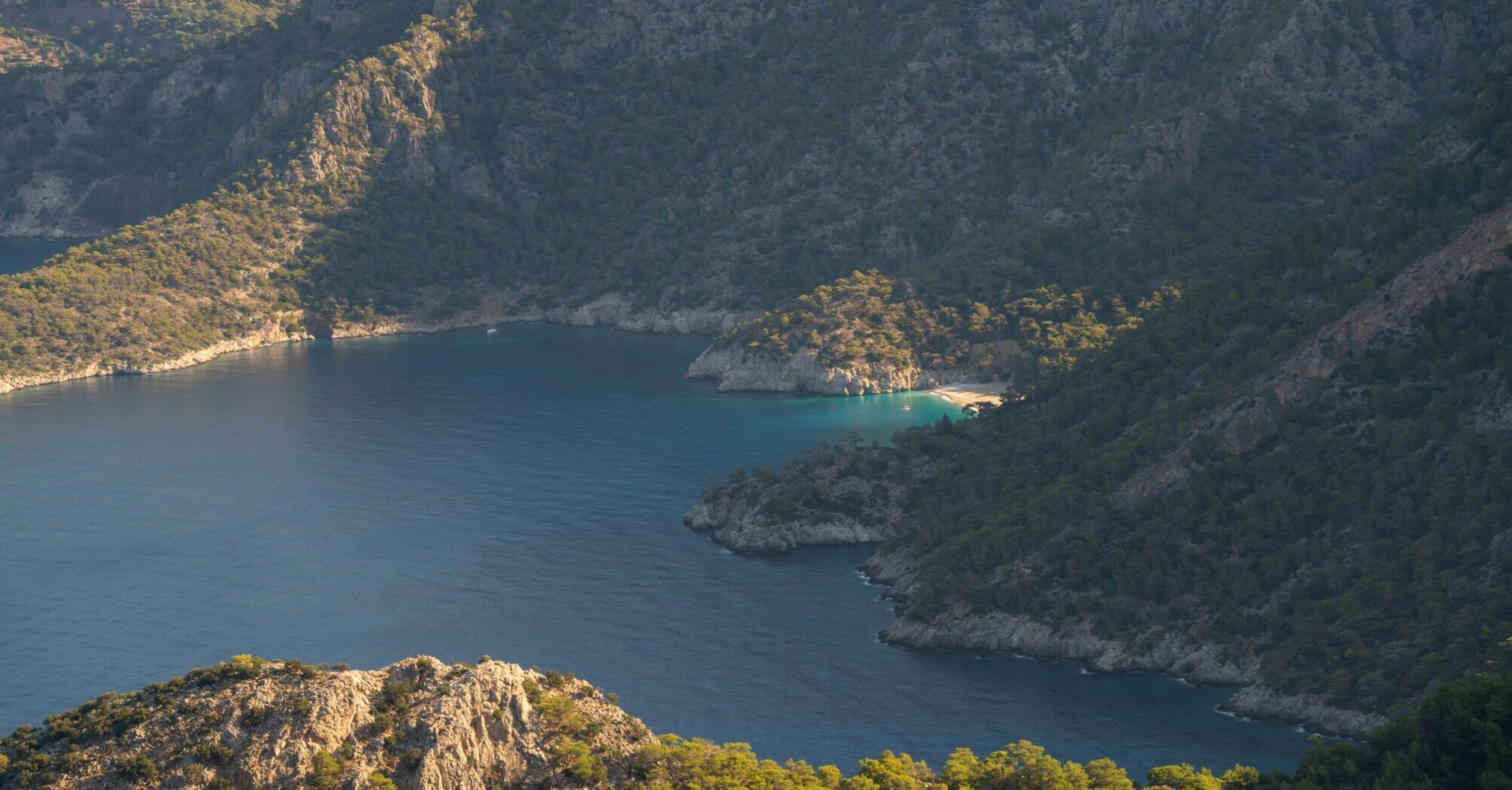 A tiny secluded beach with turquoise waters illuminated by the early morning sun, Aegean ocean, Fethiye, Turkey