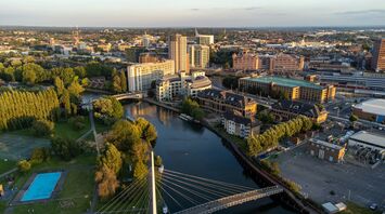 An aerial view of Reading, UK, showcasing modern buildings, a river, a bridge, and green spaces
